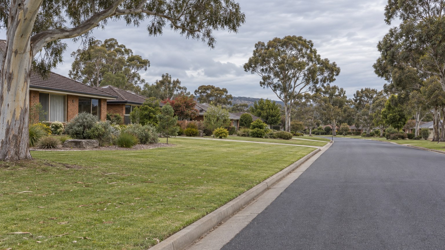 Wide suburban street with grass verge, eucalyptus trees and brick homes