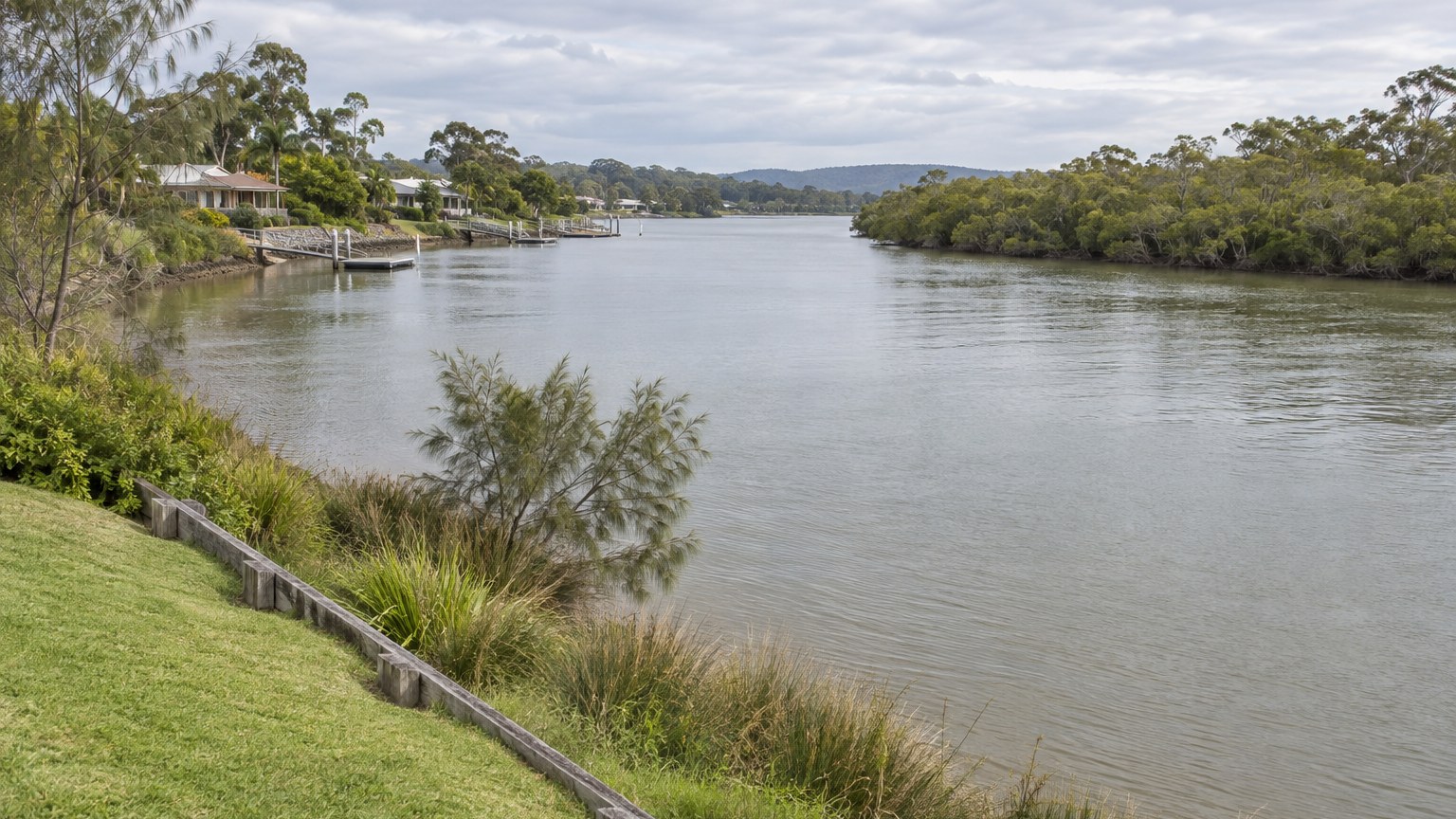Tidal river between grassy banks with mangroves on the far shore